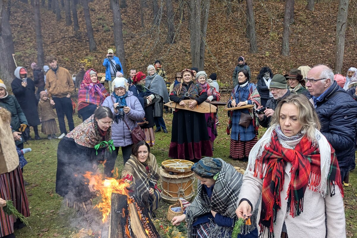 Visiteurs en costume traditionnel autour d'un feu de Mārtiņdiena au Musée ethnographique en plein air de Riga.