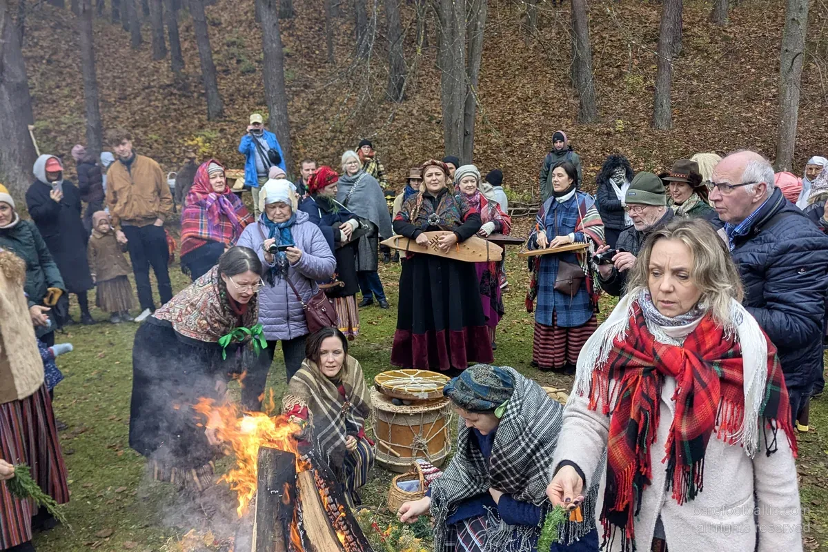 Visiteurs en costume traditionnel autour d'un feu de Mārtiņdiena au Musée ethnographique en plein air de Riga.