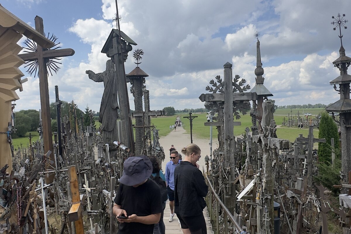 Colline des Croix, Lituanie — passerelle avec la statue du Christ et croix sculptées à la main.