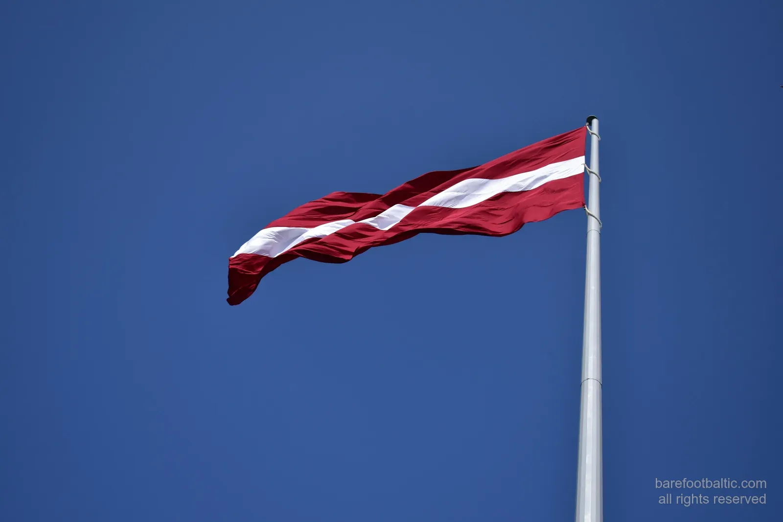 Le drapeau letton sur fond de ciel bleu