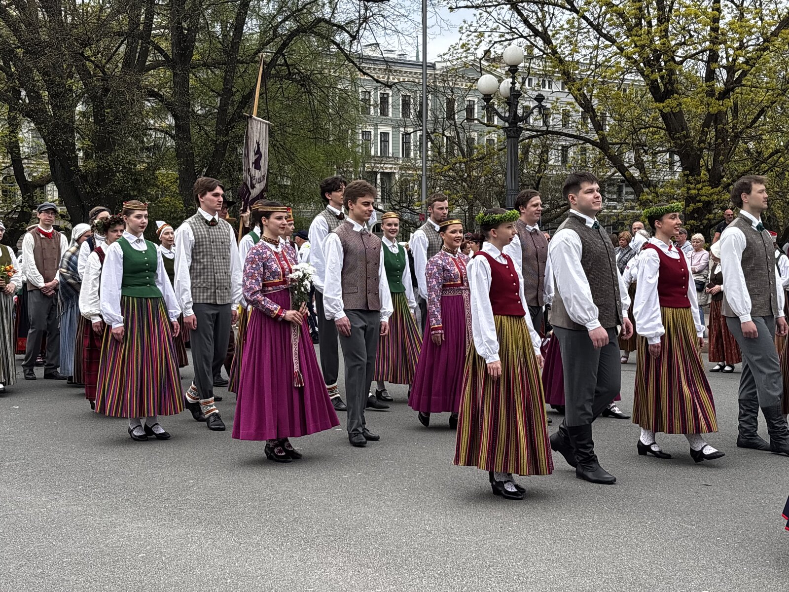 Cort&egrave;ge en costumes folkloriques devant le Monument de la Libert&eacute; avec le drapeau letton lev&eacute;, Riga, 4 mai