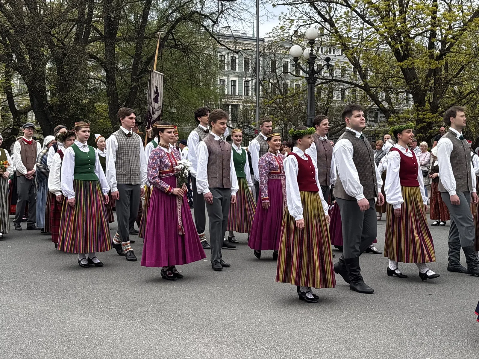 Cort&egrave;ge en costumes folkloriques devant le Monument de la Libert&eacute; avec le drapeau letton lev&eacute;, Riga, 4 mai