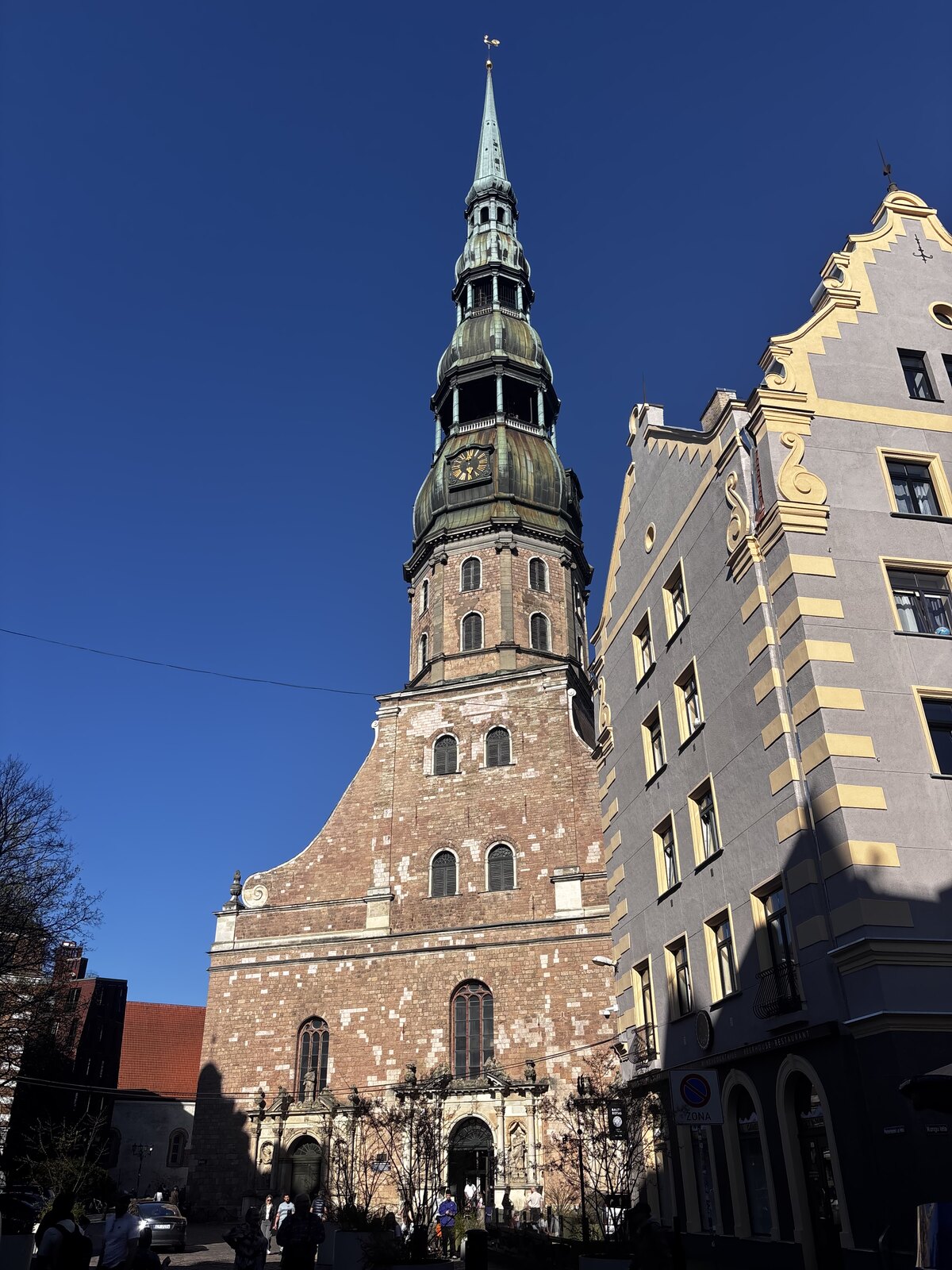 L'église Saint-Pierre (Sv. Pētera baznīca) avec sa haute flèche verte sur fond de ciel bleu, dans la vieille ville de Riga, Lettonie.