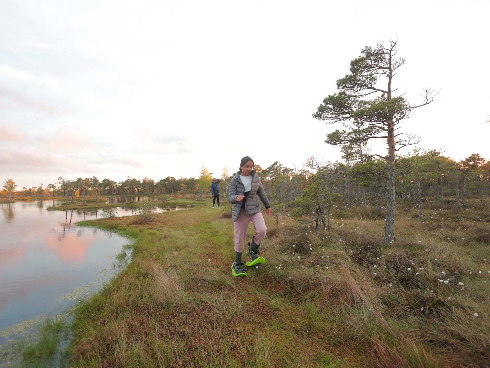 A small group in bog shoes standing at the edge of a Ķemeri bog pool
