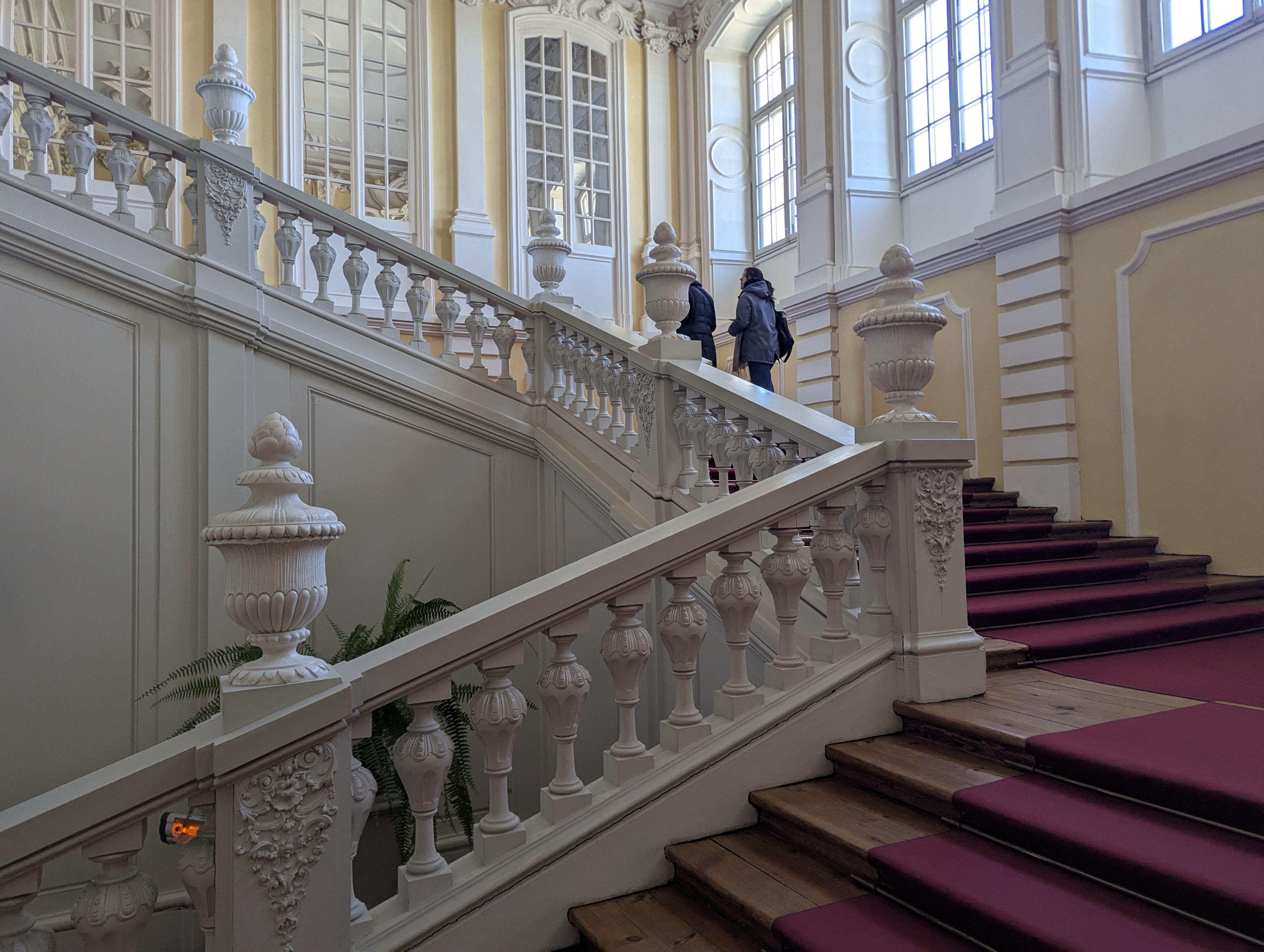 Escalier d'honneur du château de Rundāle avec balustrades en stuc blanc et tapis bourgogne