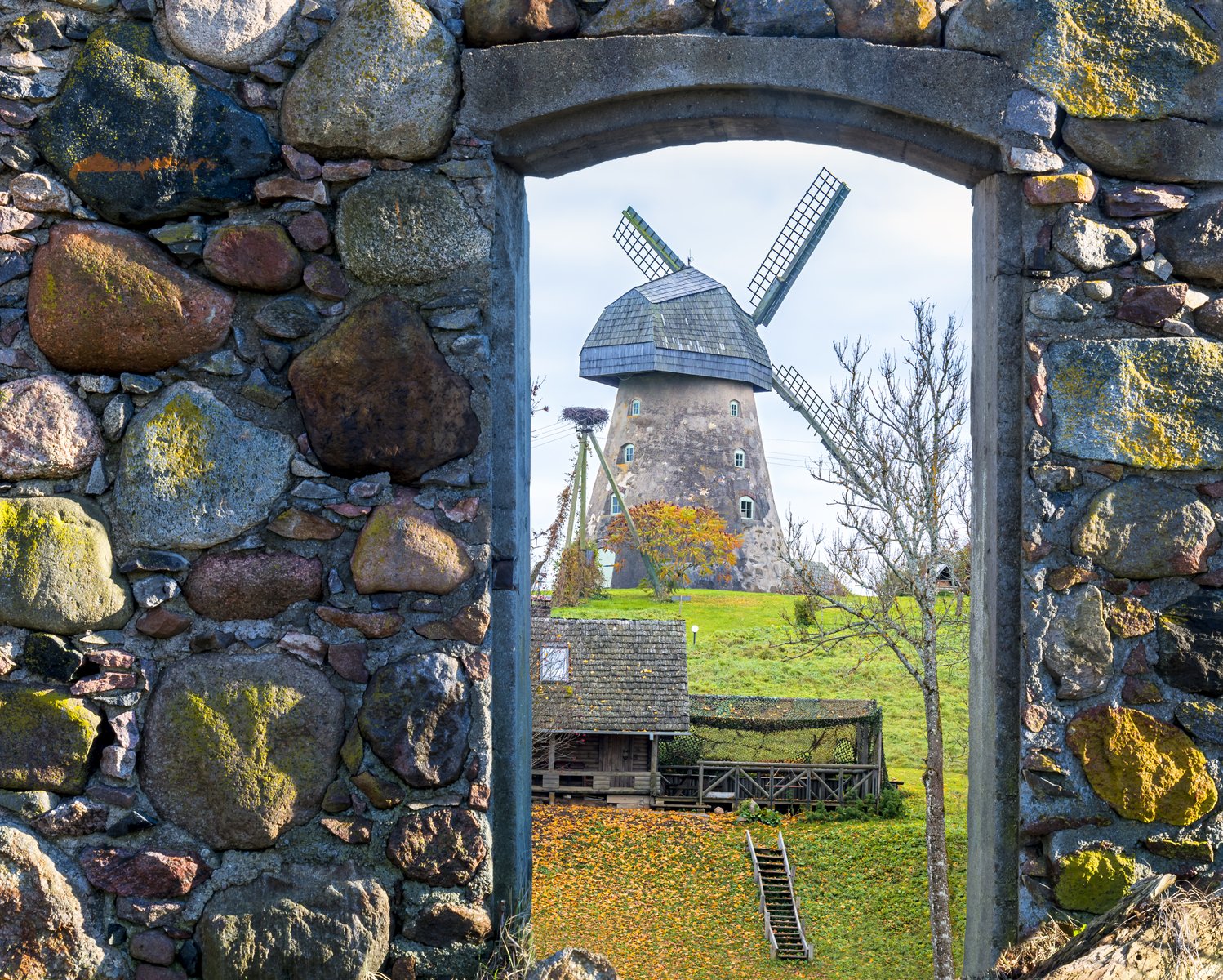 Un moulin traditionnel aperçu à travers une voûte de pierre dans une ferme de Vidzeme