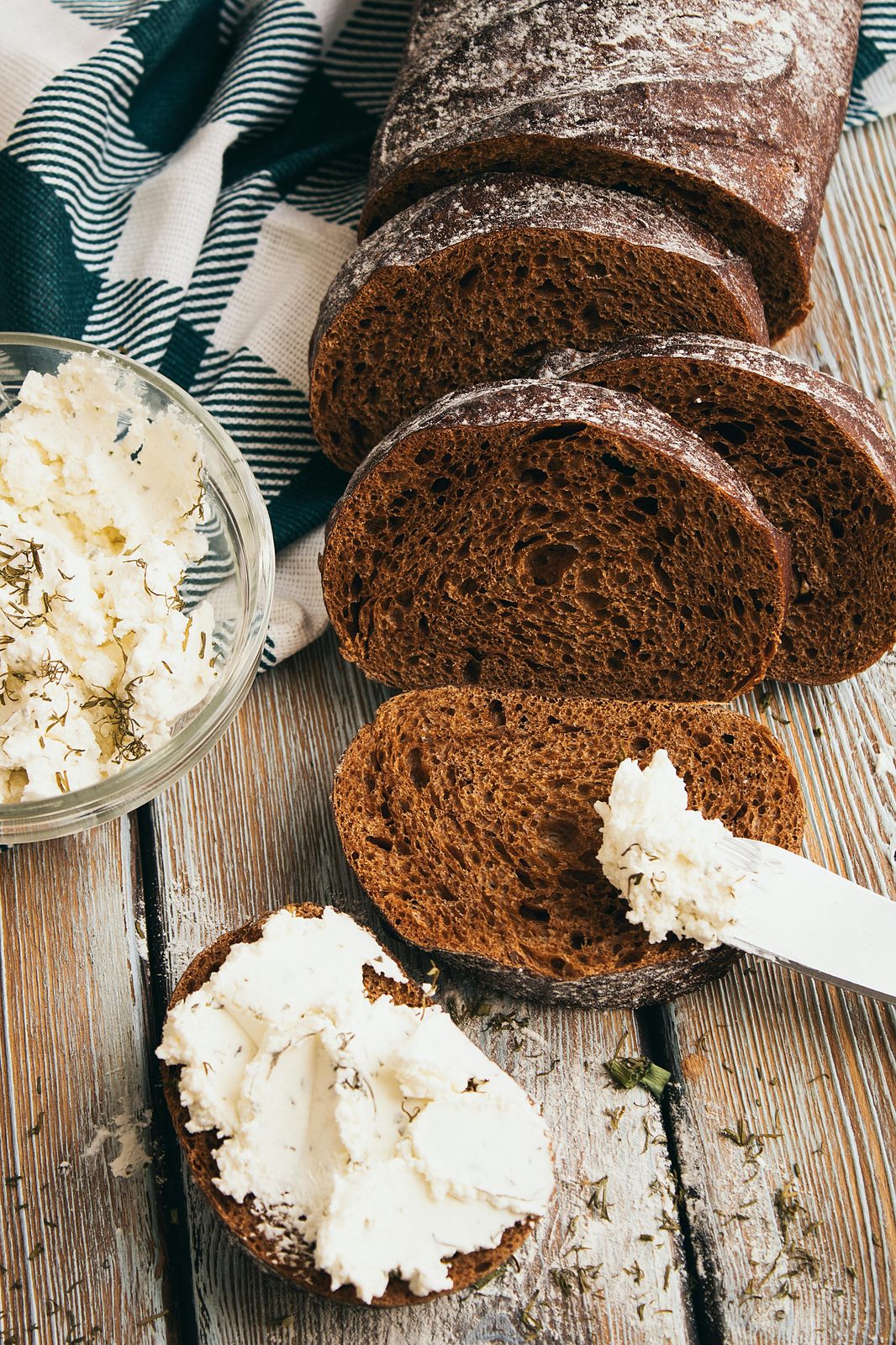Tranches de rupjmaize, le pain de seigle noir, avec un bol de biezpiens (fromage blanc) saupoudré d'aneth