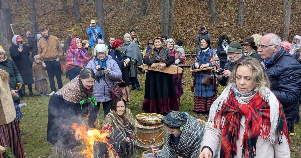 Visiteurs en costume traditionnel autour d'un feu de Mārtiņdiena au Musée ethnographique en plein air de Riga.